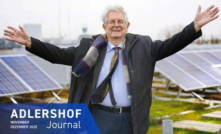 Klaus Thiessen freudig und mit erhobenen Armen vor Solarmodulen
