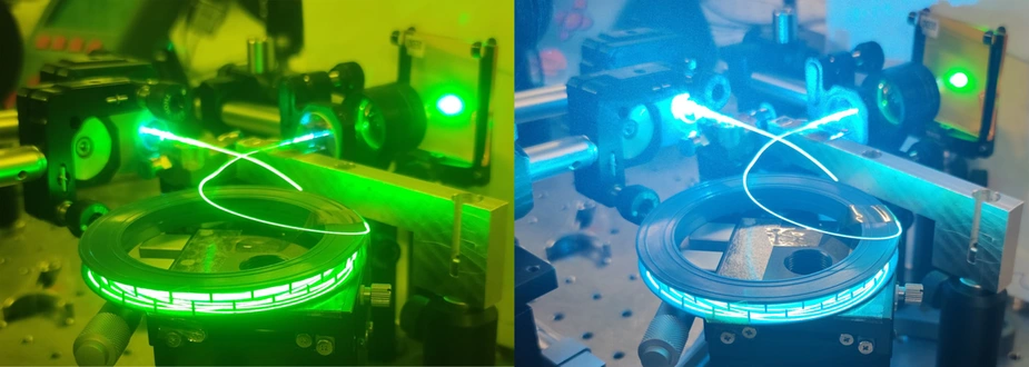 Experimenteller Laseraufbau mit leuchtenden grünen und blauen optischen Glasfasern