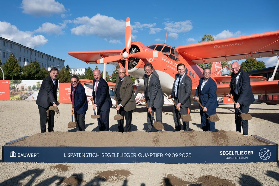 Acht Männer mit einem Spaten vor einem historischen Motorflugzeug