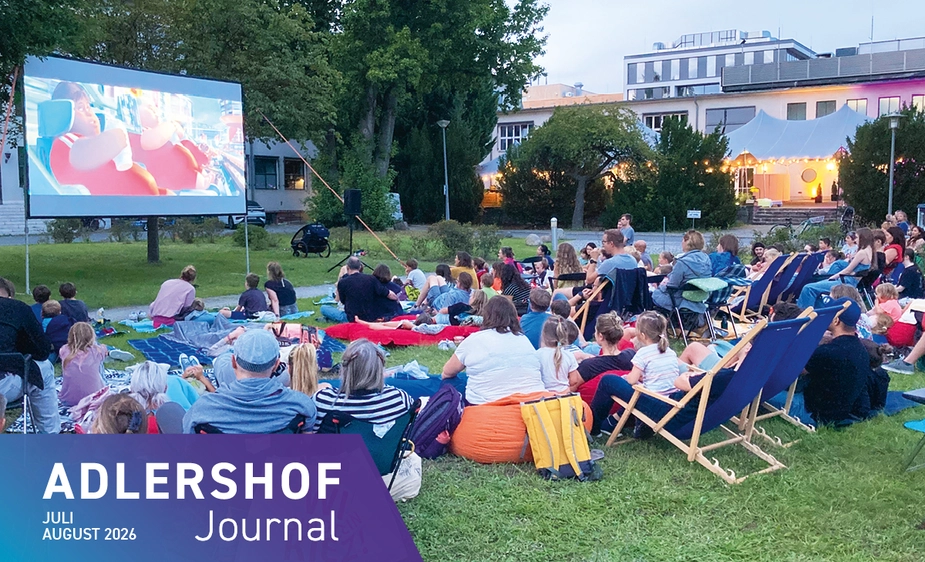 Lots of people on deckchairs and blankets on the lawn in front of the cinema screen