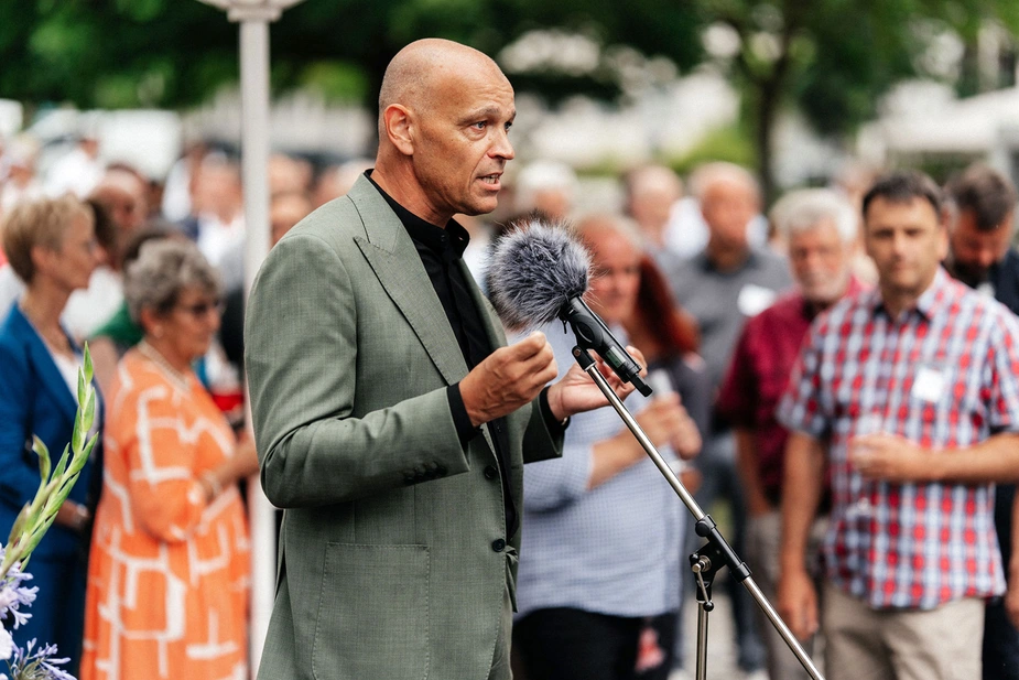 Roland Sillmann am Mikrofon, im Hintergrund Gäste
