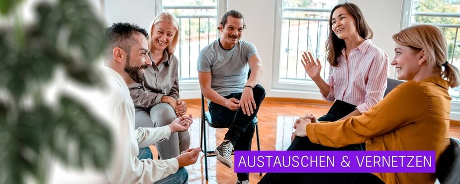 Fünf Personen sitzen im Kreis auf Stühlen in einem hellen Raum und unterhalten sich entspannt