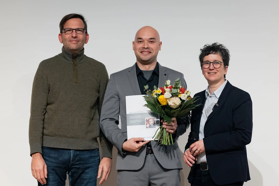 Preisträger mit Urkunde und Blumenstrauß