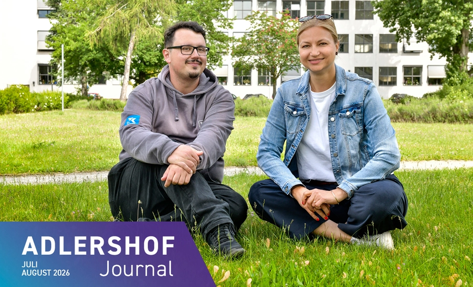 Two people sitting on the lawn in front of the WISTA building