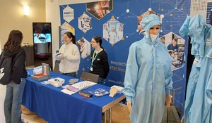 Messestand mit zwei Personen hinter einem Tisch mit Informationsmaterial und einer Schaufensterpuppe in einem blauen Schutzanzug