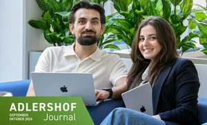Gründer und Gründerin sitzen mit ihren Laptops auf dem Schoss auf einer Couch. 